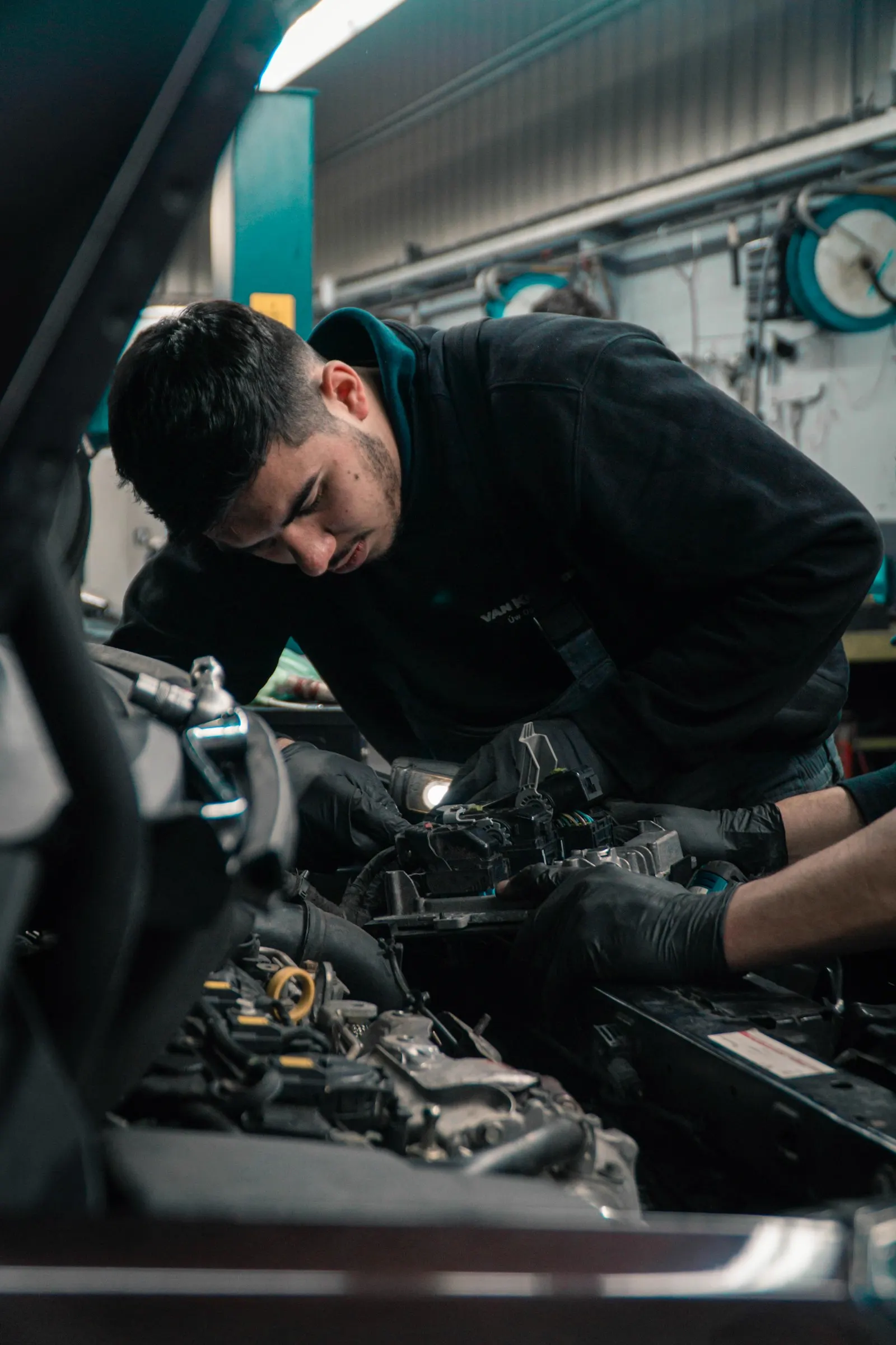 Mechanic leaning into an engine bay under the shop light