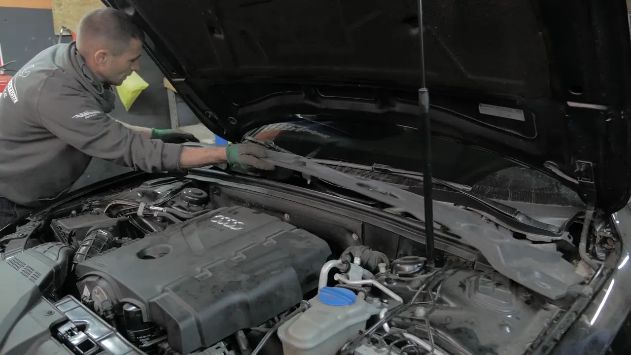 Mechanic checking components under an open hood