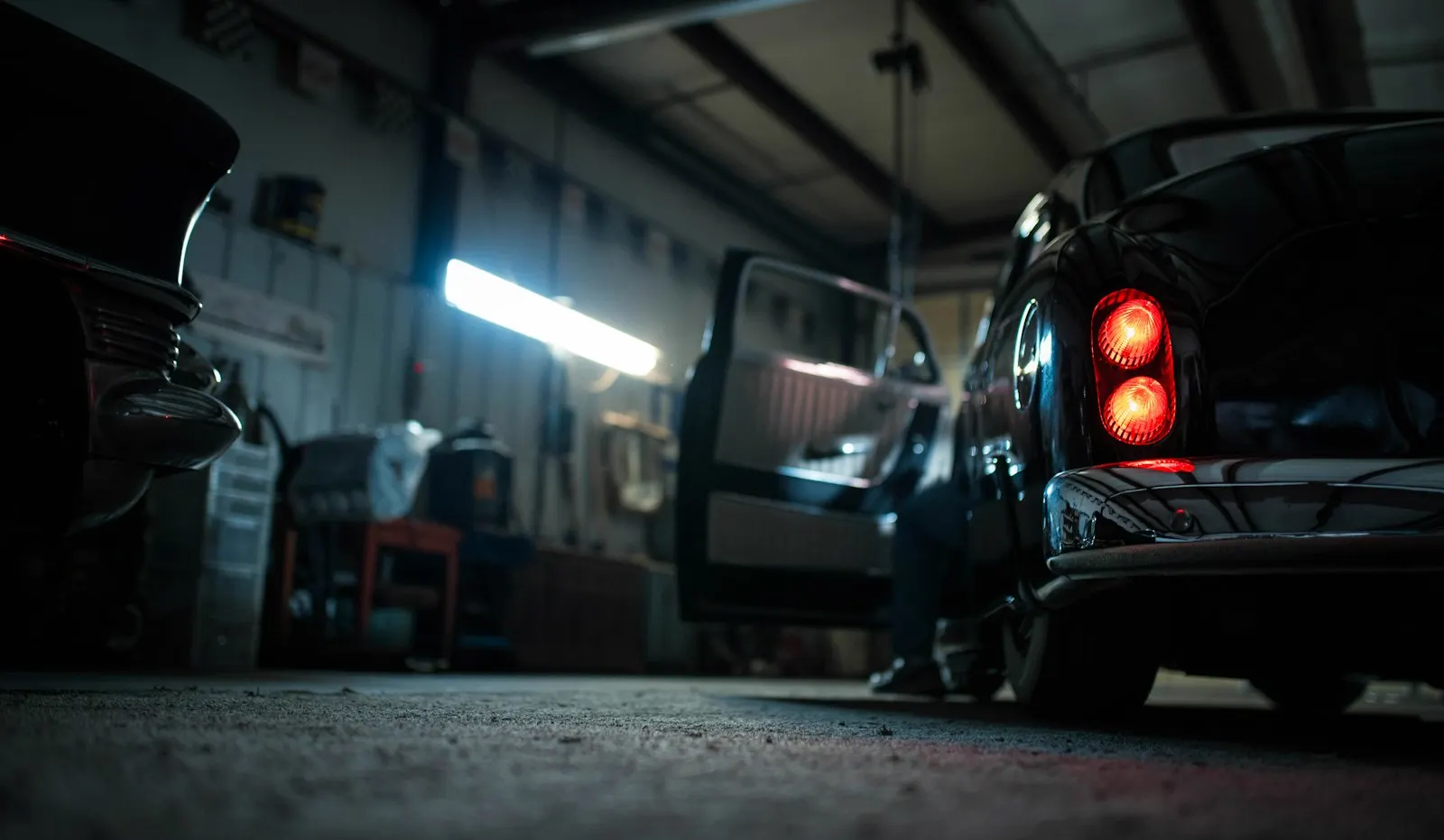A classic car with its door open in a dim workshop