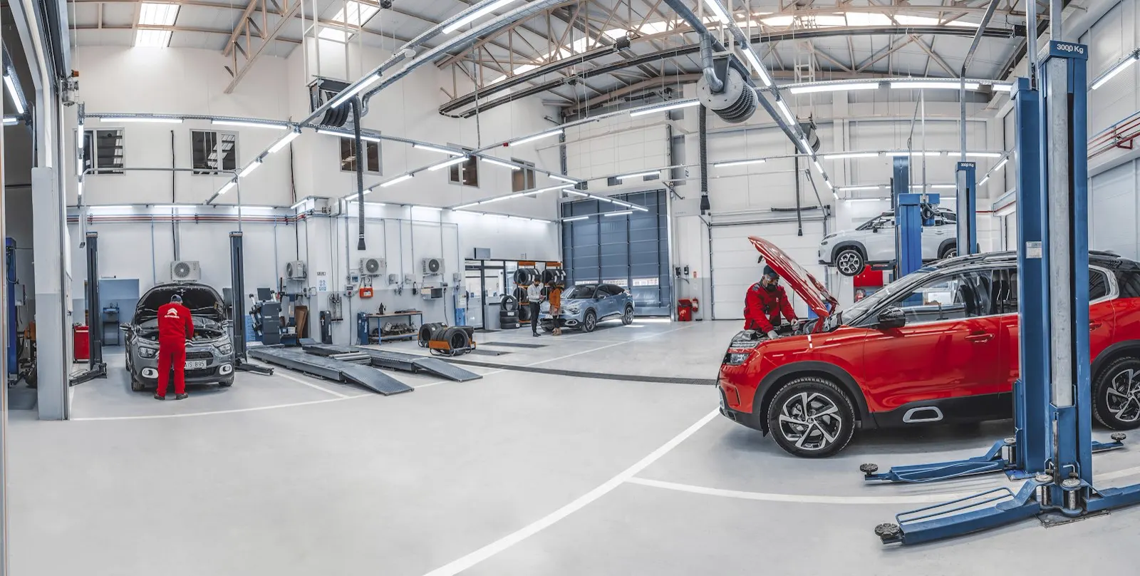 Wide view of a bright service shop with cars on lifts